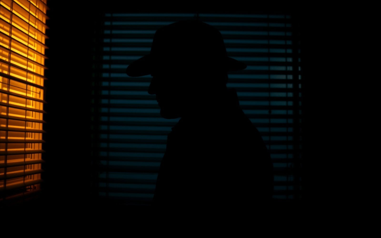 Film noir thriller still — atmospheric warm key light cutting through deep shadows, frame from a 60-sec brand film